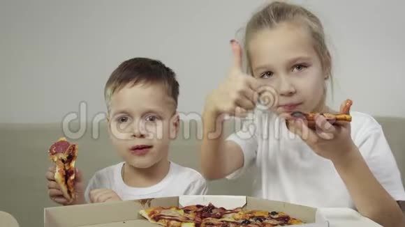 两个可爱有趣的孩子在吃披萨男孩微笑女孩笑露出她的手指概念美味视频的预览图
