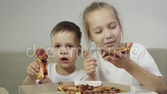 两个可爱有趣的孩子在吃披萨男孩微笑女孩笑露出她的手指概念美味视频的预览图