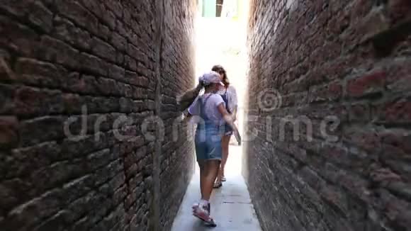威尼斯意大利2018年7月7日在威尼斯非常狭窄的街道上在老房子之间一个十几岁的女孩孩子和年轻人视频的预览图