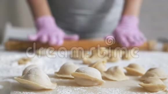 戴着亮手套的女人把面团擀在桌子上自制食物馄饨饺子视频的预览图