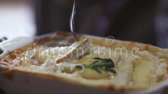 在叉子上特写热拉伸奶酪一个年轻的女人坐在餐馆里吃热千层面视频的预览图