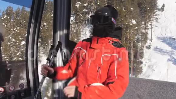 一个人在一个封闭的滑雪电梯上升到山顶男人摘下滑雪护目镜享受美丽的冬天视频的预览图