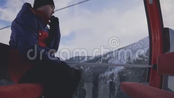 滑雪者坐在滑雪椅上打电话坐在山顶上视频的预览图
