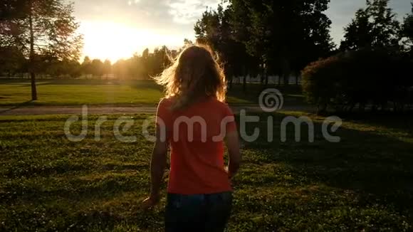 超级慢动作一个女人在阳光的映衬下在草地上慢跑视频的预览图