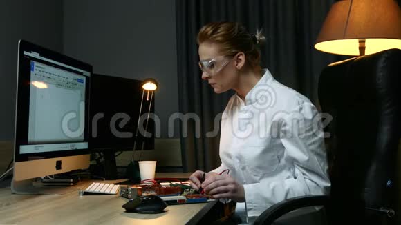 女IT工程师修理电子设备的缺陷用电子传感器和电脑坐在桌子旁视频的预览图