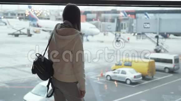 背着背包的女孩看着窗外的飞机挥动她的手视频的预览图