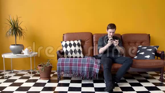 坐在沙发上打电话的家伙库存录像年轻人热情地打电话坐在时髦的地方视频的预览图