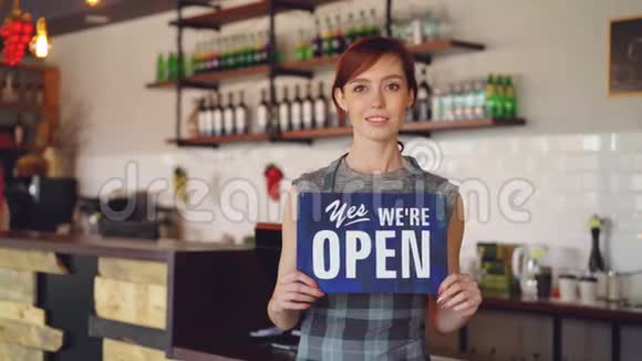 自信的女人的肖像小企业主拿着我们开门标志站在她的咖啡店里微笑视频的预览图