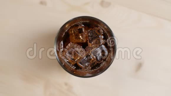 在浅棕色的木桌上放满了冰块的可乐汽水杯视频的预览图