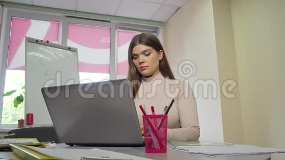 疲惫的女学生在手提电脑上揉太阳穴视频的预览图