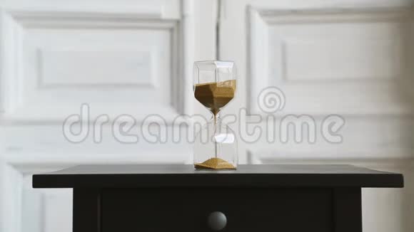 玻璃灯背景站在黑色床头柜上金色的沙子磨损视频的预览图
