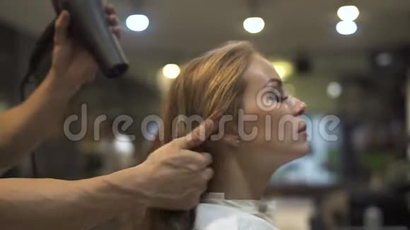 美丽的女人在美容院洗完头后用烘干机烘干头发使用吹风机的发型师视频的预览图