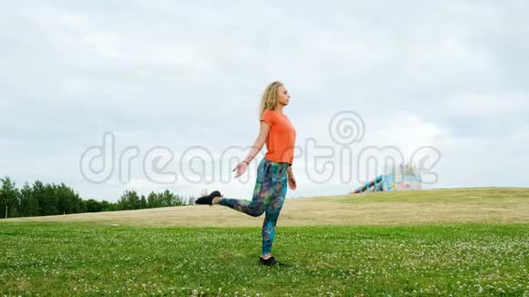 女孩在大自然中从事健身活动女孩体操运动员在城市公园里抬起腿视频的预览图