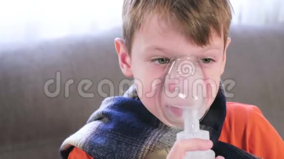 生病的金发男孩通过吸入面罩吸入使用雾化器和吸入器进行治疗视频的预览图