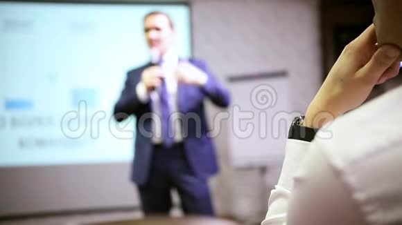 大厅里的会议台上说话的男人一个穿白衬衫的人在听讲座视频的预览图