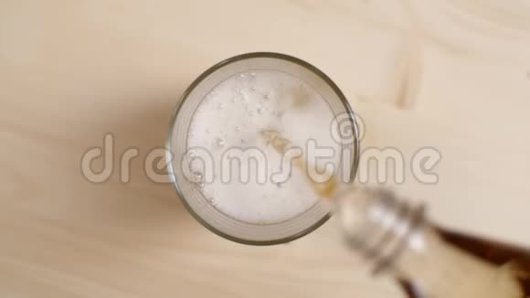 在浅棕色的木桌上倒入带有冰块的玻璃杯中的奶油苏打水饮料的俯视图视频的预览图