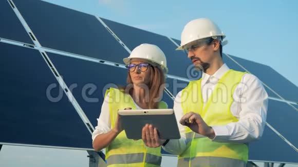两名工人站在太阳能电池板附近一个平板电脑关闭视频的预览图