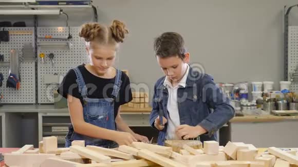 年轻的孩子在车间里小小的建筑理念从事木工工作的儿童男孩在木板上钉钉子视频的预览图