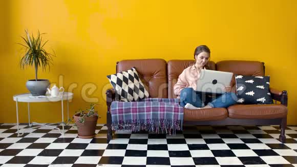 年轻漂亮的女人在客厅的笔记本电脑上辛勤工作库存录像年轻漂亮的女士在电脑上打字视频的预览图