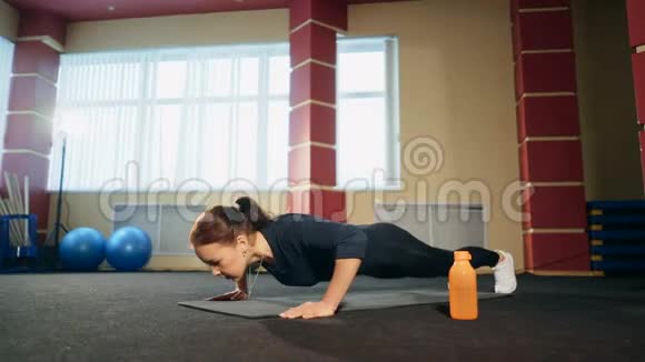 布鲁内特女士在健身房加强俯卧撑锻炼视频的预览图