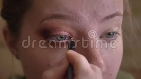 年轻的白种人女性化妆师用白色眼线在眼角的特写肖像视频的预览图