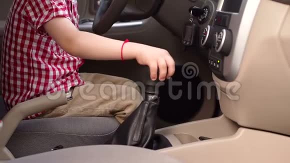 快乐的小男孩坐在汽车的车轮后面玩特写镜头视频的预览图