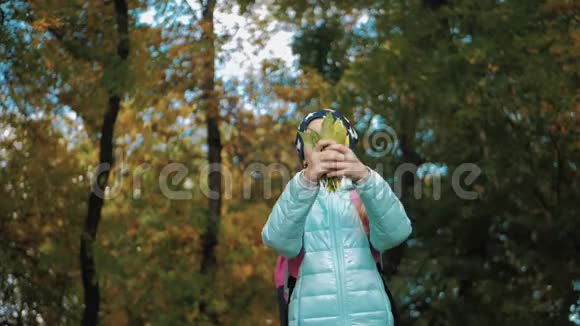 快乐的女孩把落叶扔了起来在秋天的公园里玩视频的预览图