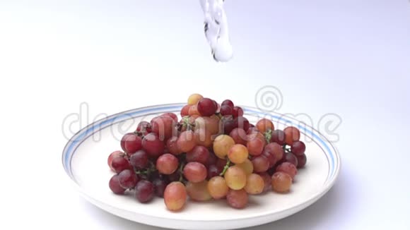 把新鲜的水倒在白色盘子里的一堆葡萄上视频的预览图