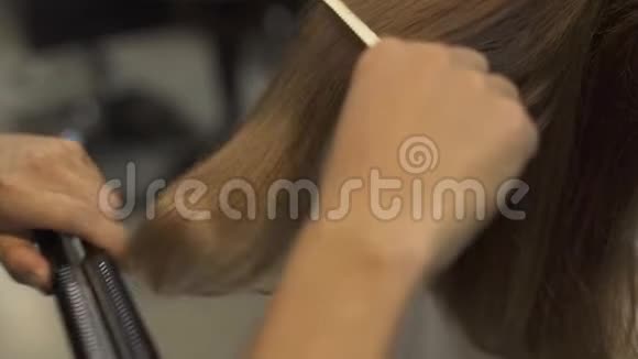 在专业美容工作室里头发发烫的长发发型师为长发做矫直视频的预览图