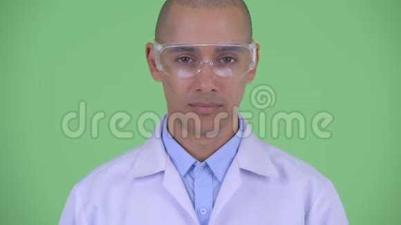 戴着防护眼镜的快乐秃顶多民族医生脸上露出微笑视频的预览图