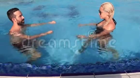 热情的男人和女人在游泳池里游泳时亲吻和拥抱的慢动作视频的预览图