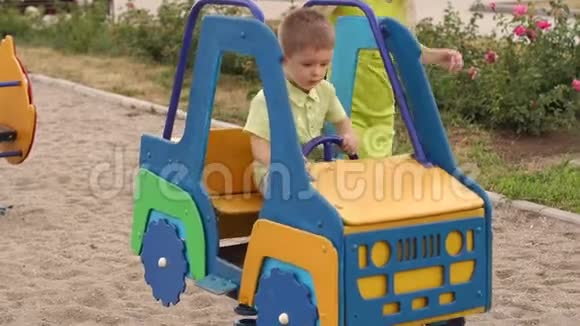 一个小男孩坐着玩具车在操场上玩他妈妈站在旁边视频的预览图