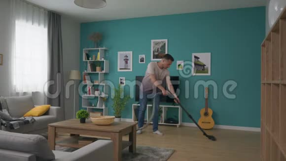 全镜头男人清洁舒适公寓与吸尘器视频的预览图