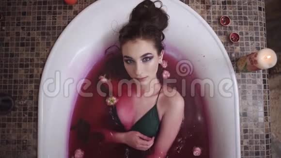 美丽温柔的年轻女人的肖像明亮的化妆放松洗澡与玫瑰在水疗沙龙可爱的女孩视频的预览图
