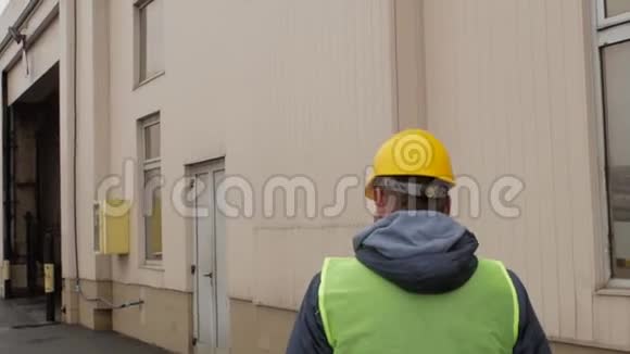 一个留着胡子和头盔的海港工人正在走路背面视图视频的预览图