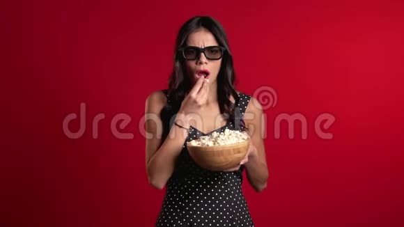 戴3D眼镜看恐怖电影吃红爆米花的年轻女性视频的预览图