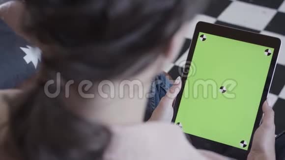 年轻的黑发女人看着她的平板电脑绿色屏幕在黑白地板背景库存录像侧视图视频的预览图