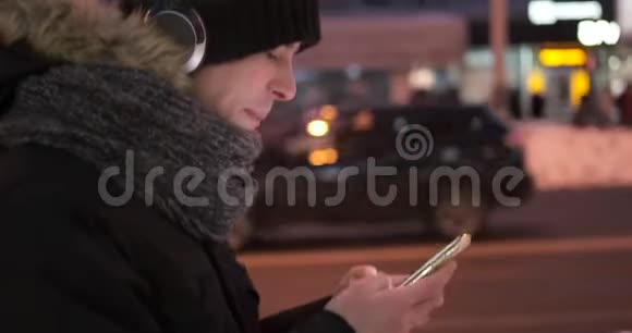 在寒冷的冬夜人们用耳机听音乐用手机视频的预览图