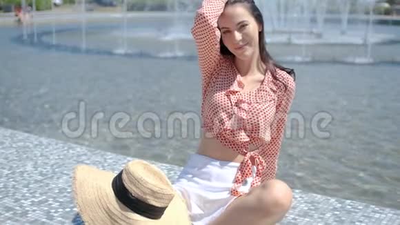夏天美丽的女人在城市喷泉旁边摆姿势视频的预览图