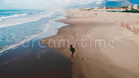 航空无人驾驶飞机女孩游客跑沿海滩维亚雷吉奥意大利波浪线牛仔裤自由概念视频的预览图