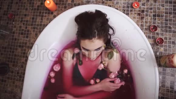 化妆鲜艳的年轻女人用玫瑰洗澡从上面拍摄俯视慢动作视频的预览图