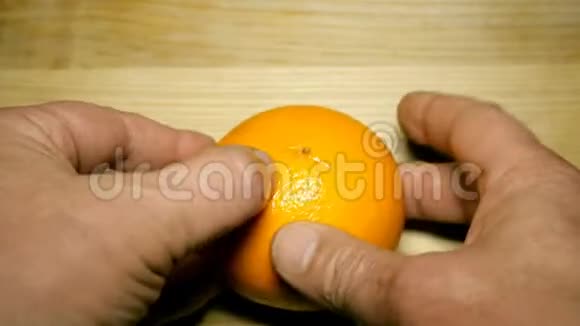 人类的手在木桌上剥去多汁的橘子视频的预览图