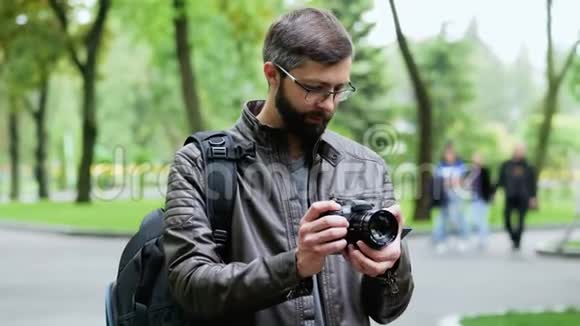 带着相机的快乐胡子男人在公园里拍照视频的预览图