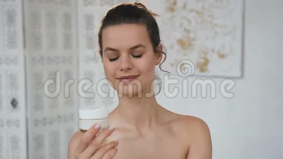 漂亮的年轻女人在白色浴室里打开带有奶油的罐子视频的预览图
