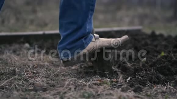 一个穿着蓝色牛仔裤男人的腿在地上挖铲子视频的预览图