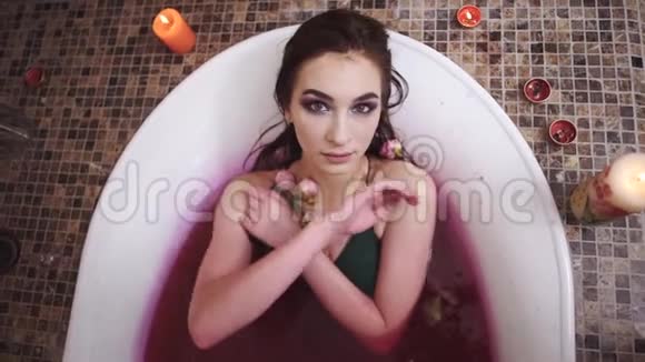 美丽的年轻女子化妆鲜艳用玫瑰洗澡漂亮的女孩在浴室里尽情地享受着燃烧视频的预览图