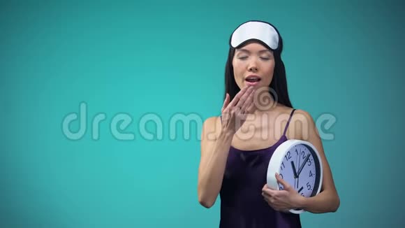 穿着睡衣的年轻女子打哈欠手里拿着钟伸懒腰视频的预览图