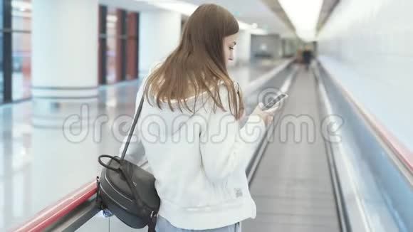 在国际机场的移动通道上欧洲妇女在手机上发短信视频的预览图