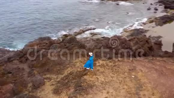 从高处看穿着漂亮的蓝色连衣裙和帽子的妇女站在保护区的山顶上视频的预览图