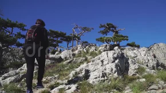 年轻女子背着背包爬上山顶视频的预览图